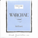 A product label for Warchal Brilliant Viola Large A string, featuring a light blue square with black and white text. The handwritten phrase "sound fascinates us" appears at the bottom.